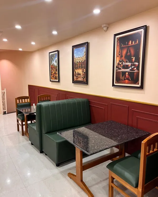 Marble-look tables, wooden chairs and green booths along the dining room