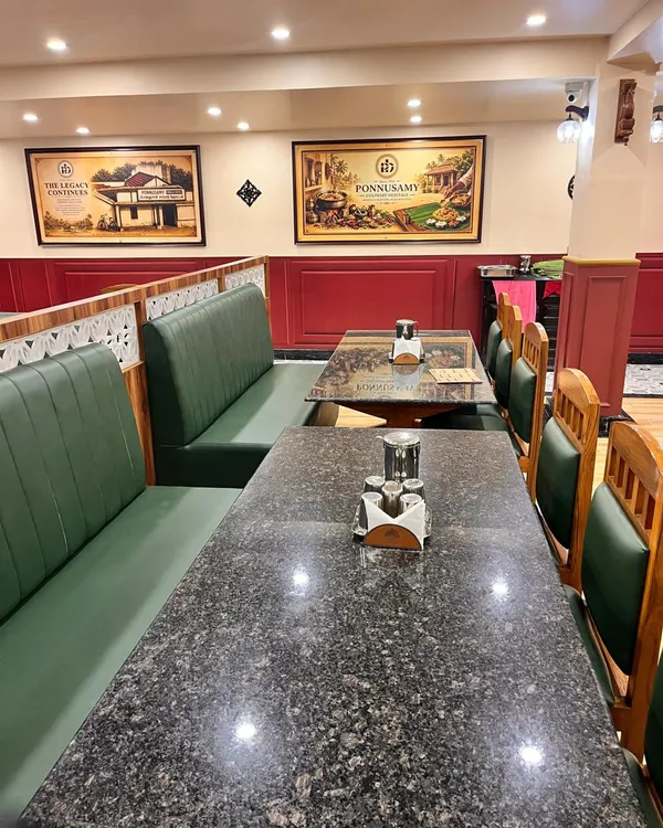 Long dining table set with steel tumblers beside green upholstered seating