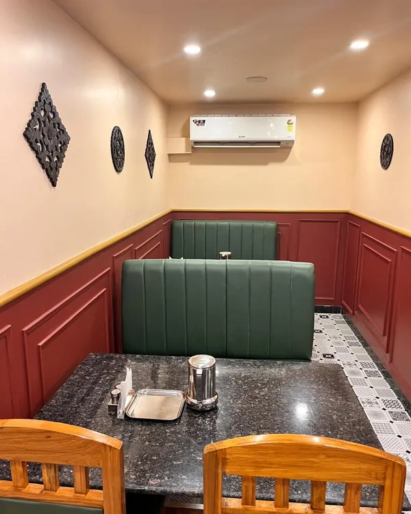 A dining nook with a dark tabletop, wooden chairs and green bench seating